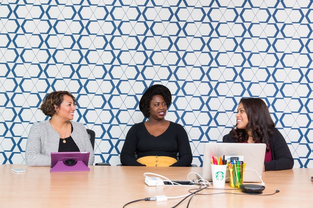 three women sitting in front of a wooden table